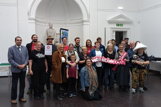 A group photo showing the winners of the your pots funding in a white hall