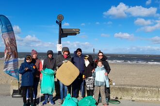 seven people stood with litter picking equipment and full bags next to the beach in Fleetwood
