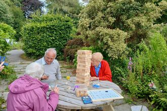 A group of people playing Jenga in the sunshine.
