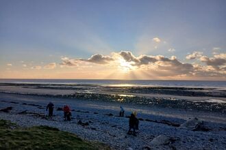 A group of people picking litter on a beach.