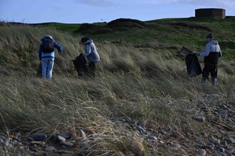 Three people litter picking on the upper shore.