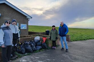 A group of people by litter by a beach.