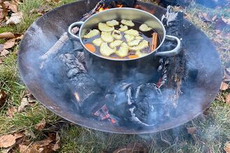 Mulled juice being cooked over a firepit
