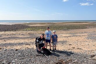 A man and two children during a beach clean.