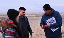 Two people look at shark eggcases held by a staff member