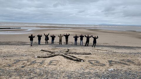 10 people lined up behind a sand art starfish