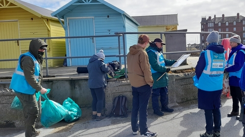 A beach cleaning team of volunteers by the huts in Fleetwood