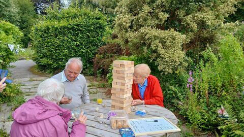 A group of people playing Jenga in the sunshine.