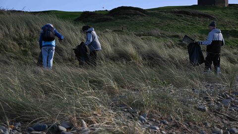 Three people litter picking on the upper shore.