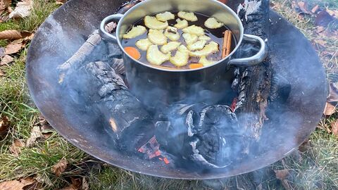Mulled juice being cooked over a firepit