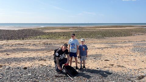 A man and two children during a beach clean.