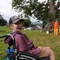 A young man in a wheelchair wearing a baseball cap and smiling