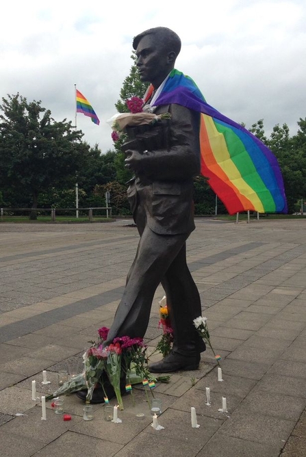 A statue of Alan Turing draped in a rainbow flag