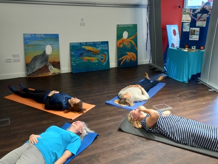 Four people on yoga mats meditating