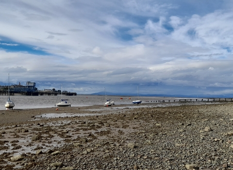 A landscape view of Knott end beach with several boats on the shore